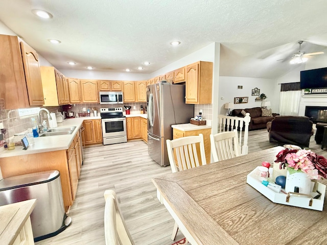 kitchen featuring ceiling fan, appliances with stainless steel finishes, a sink, light countertops, and decorative backsplash