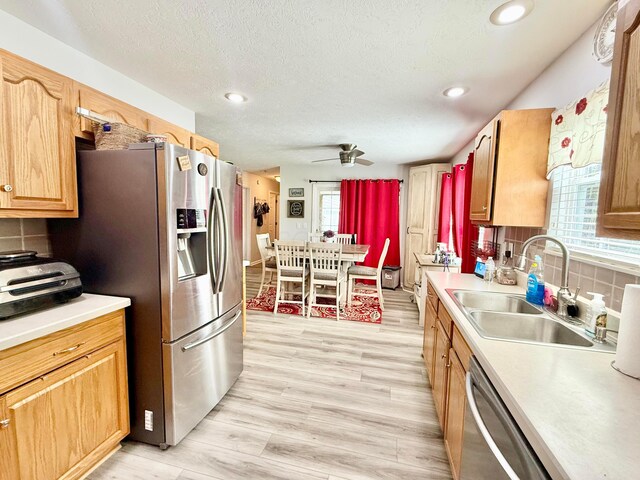 kitchen with backsplash, stainless steel appliances, ceiling fan, and a sink