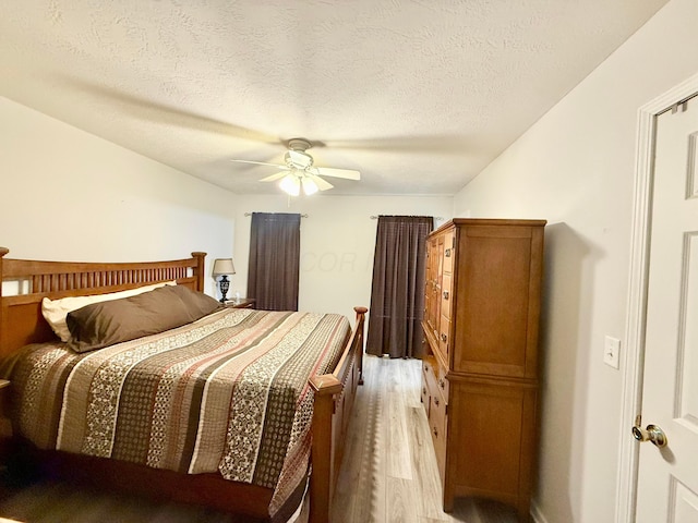 bedroom featuring ceiling fan, light wood-type flooring, and a textured ceiling