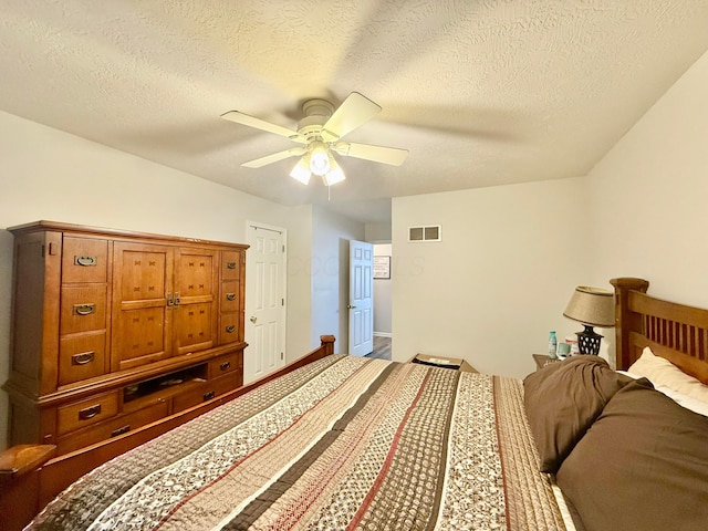 bedroom featuring a ceiling fan, a textured ceiling, and visible vents