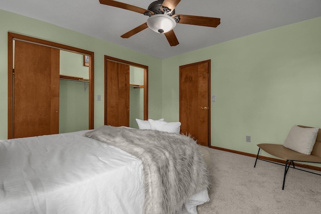 bedroom featuring ceiling fan, light carpet, baseboards, and multiple closets