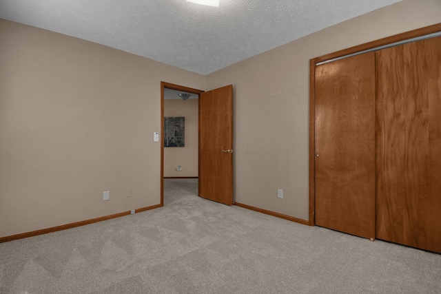 unfurnished bedroom featuring baseboards, a textured ceiling, a closet, and carpet floors