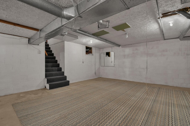 unfinished basement with concrete block wall and stairs