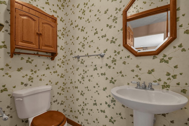 bathroom featuring toilet and wallpapered walls