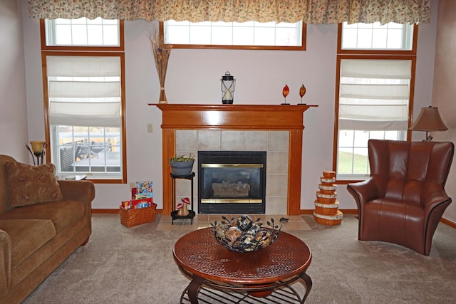 carpeted living room with a tiled fireplace and baseboards