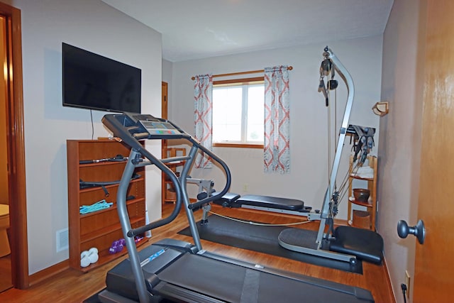 workout area with baseboards and wood finished floors