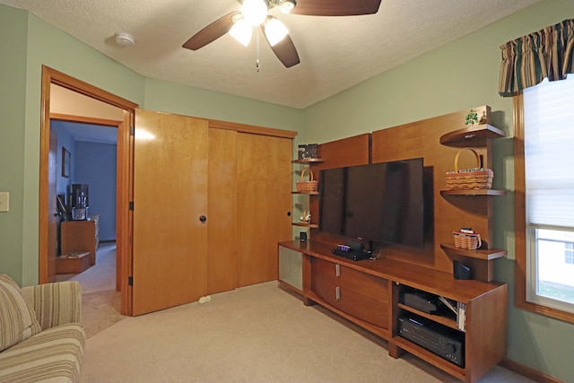 living room with ceiling fan, light carpet, and a textured ceiling