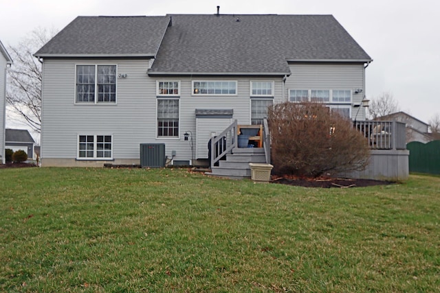 rear view of property featuring a lawn, central AC, a deck, and roof with shingles