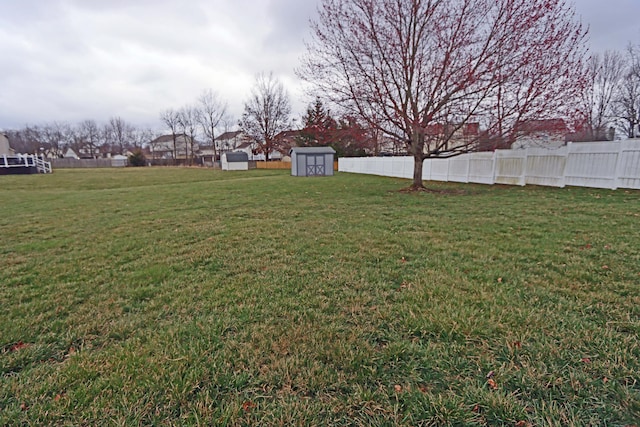 view of yard featuring a storage unit, an outdoor structure, and fence