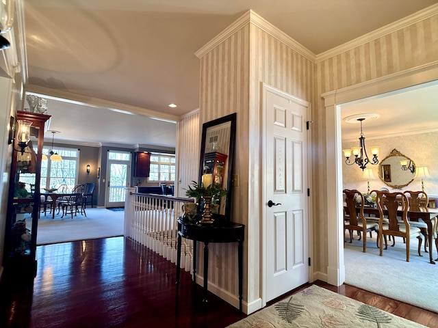hallway with wallpapered walls, baseboards, a chandelier, ornamental molding, and wood finished floors