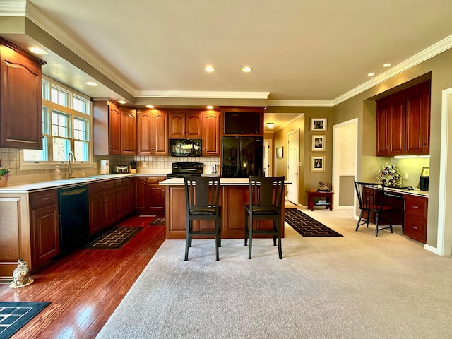 kitchen featuring decorative backsplash, black appliances, light countertops, and a sink