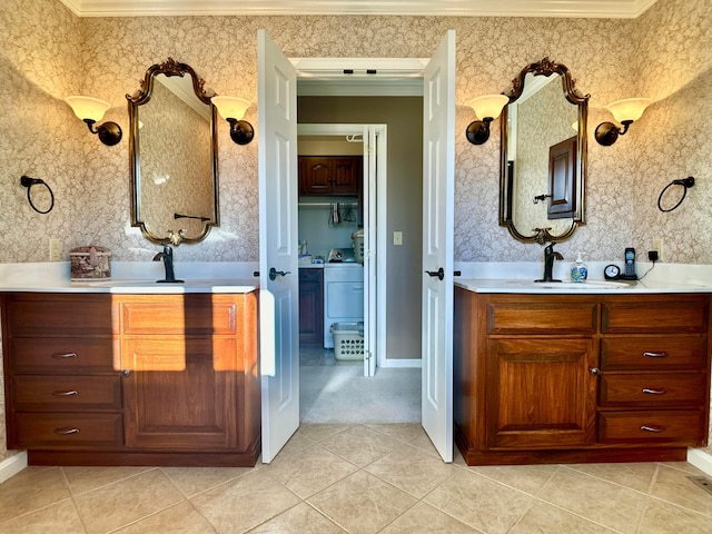 bathroom with wallpapered walls, two vanities, ornamental molding, a sink, and tile patterned floors