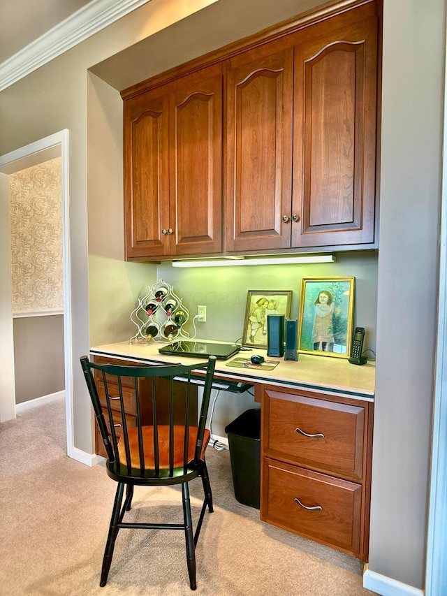 office area featuring baseboards, light carpet, ornamental molding, and built in study area