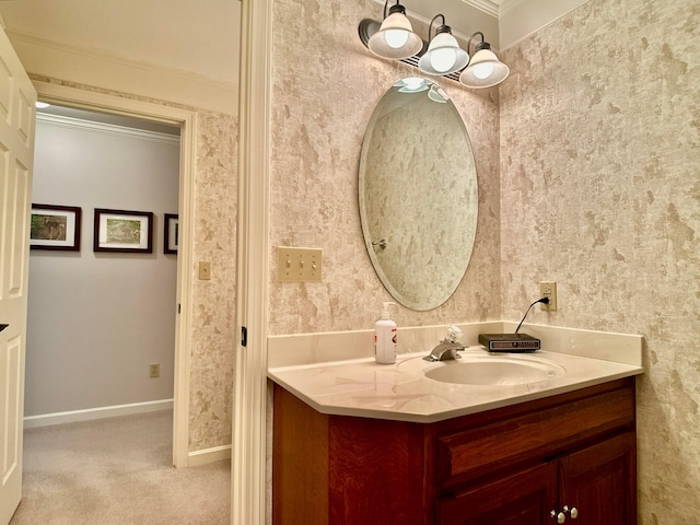 bathroom featuring baseboards, crown molding, vanity, and wallpapered walls