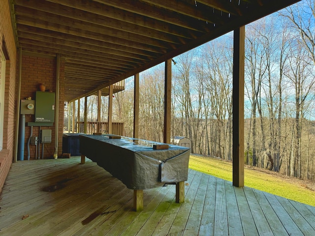 wooden terrace featuring an outbuilding, a lawn, and a view of trees