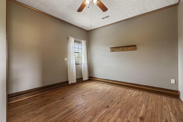 spare room featuring crown molding, visible vents, wood finished floors, ceiling fan, and a textured ceiling