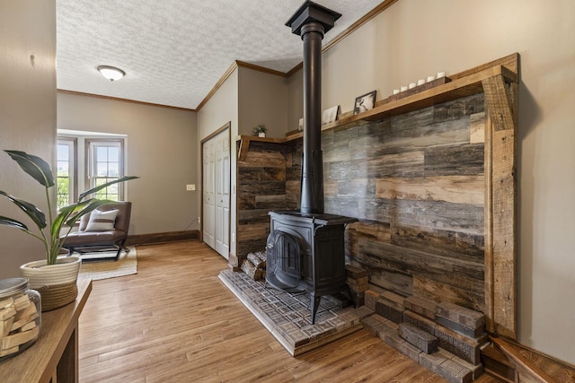 interior space with crown molding, a wood stove, a textured ceiling, and wood finished floors