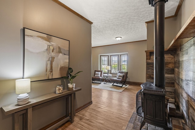 interior space featuring crown molding, baseboards, light wood-type flooring, and a textured ceiling