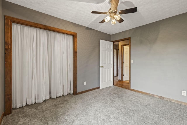 unfurnished bedroom with baseboards, ceiling fan, carpet flooring, and a textured ceiling