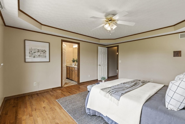 bedroom with crown molding, a raised ceiling, light wood-style flooring, baseboards, and visible vents
