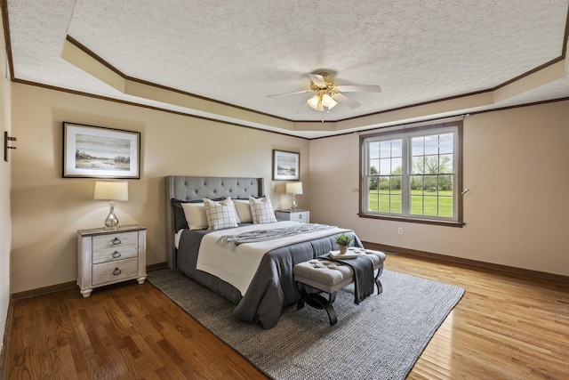 bedroom with ornamental molding, a textured ceiling, and wood finished floors