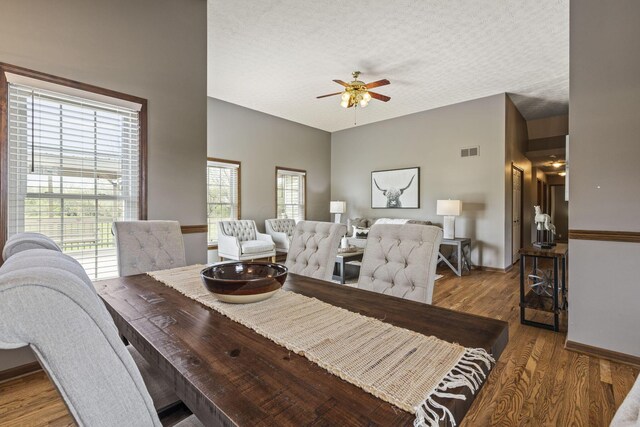 dining room with ceiling fan, a textured ceiling, visible vents, wood finished floors, and baseboards