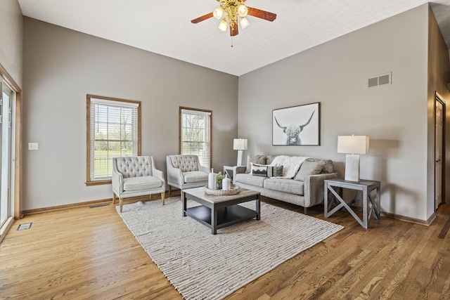 living room with baseboards, ceiling fan, wood finished floors, and visible vents