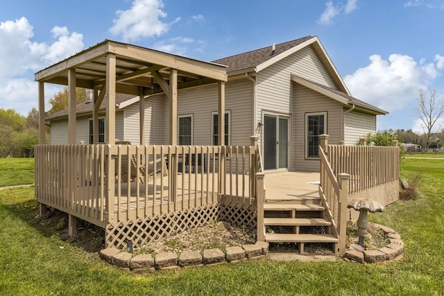 rear view of property featuring a shingled roof, a yard, and a deck