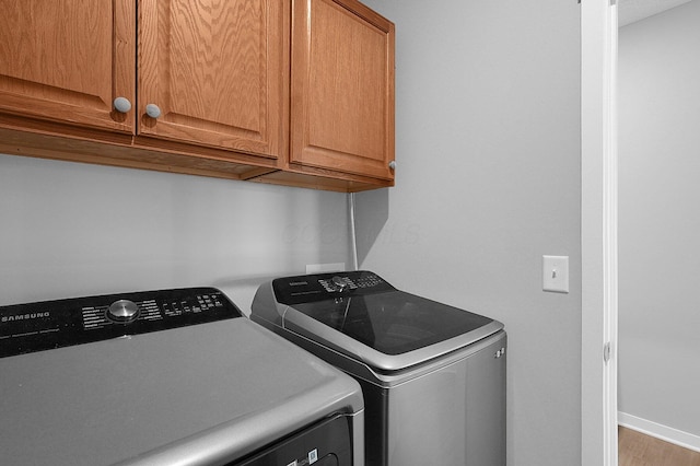 laundry area featuring washer and dryer, cabinet space, and baseboards