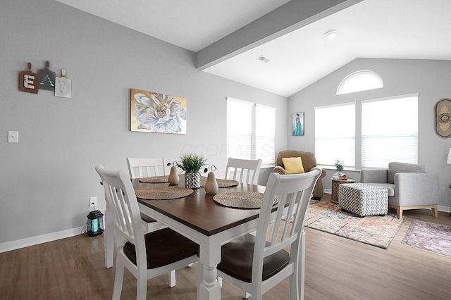 dining room with visible vents, baseboards, lofted ceiling, and wood finished floors