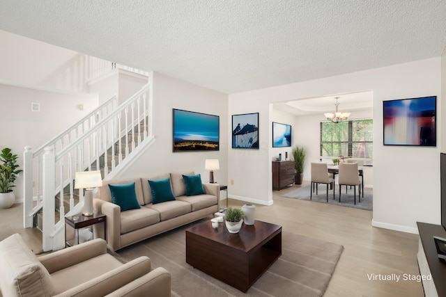 living area featuring baseboards, a notable chandelier, wood finished floors, and a textured ceiling