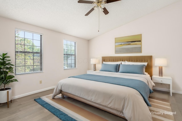 bedroom with lofted ceiling, baseboards, a textured ceiling, a ceiling fan, and wood finished floors