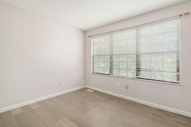 unfurnished room featuring baseboards, a textured ceiling, and light wood-type flooring