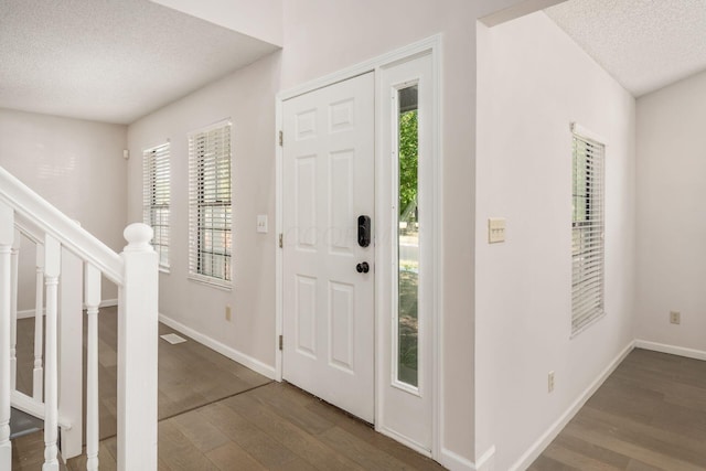 entrance foyer with baseboards, wood finished floors, stairway, and a textured ceiling