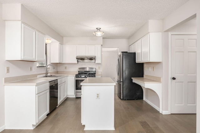 kitchen with white cabinets, wood finished floors, stainless steel appliances, a sink, and exhaust hood