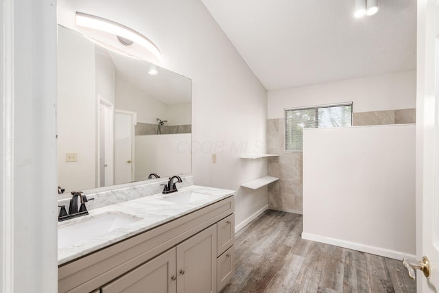 full bath with lofted ceiling, wood finished floors, a sink, and walk in shower