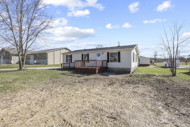 manufactured / mobile home with a wooden deck, a front yard, and a shingled roof