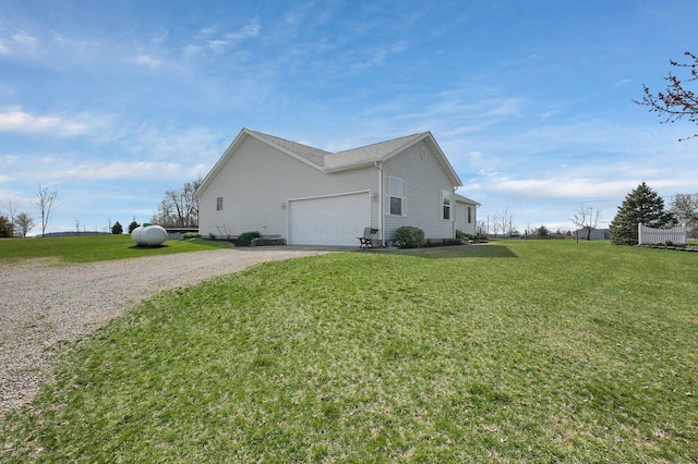 view of side of property with gravel driveway, a yard, and an attached garage