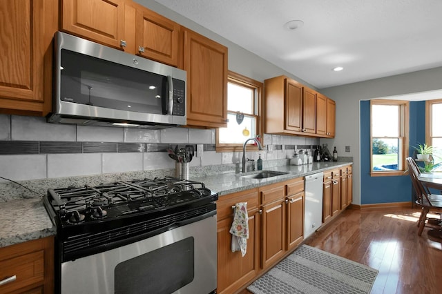kitchen featuring a sink, a healthy amount of sunlight, brown cabinets, and appliances with stainless steel finishes