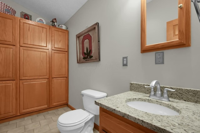 bathroom with tile patterned floors, toilet, vanity, and a textured ceiling