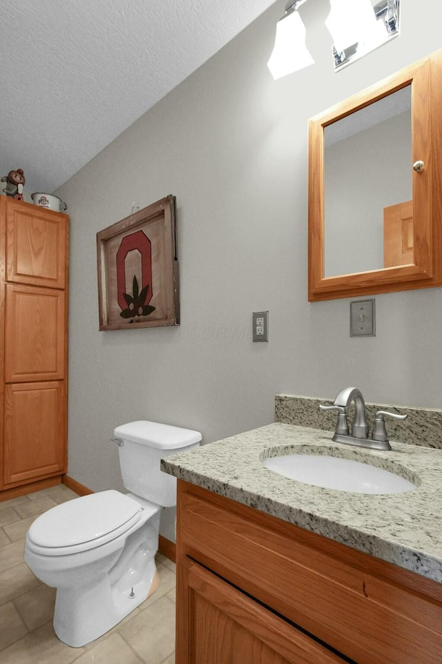 bathroom with tile patterned flooring, vanity, toilet, and a textured ceiling