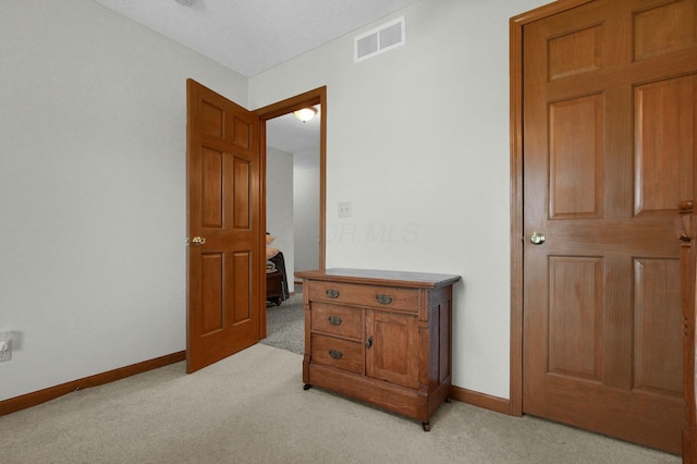 bedroom with baseboards, visible vents, and light carpet