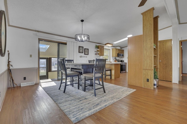 dining area featuring visible vents, light wood-style floors, a textured ceiling, crown molding, and ceiling fan with notable chandelier