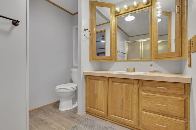 full bath featuring wood finished floors, toilet, vanity, and ornamental molding