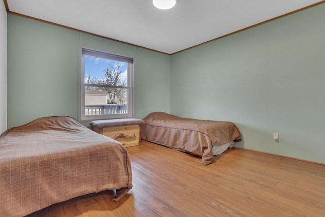 bedroom with wood finished floors and ornamental molding