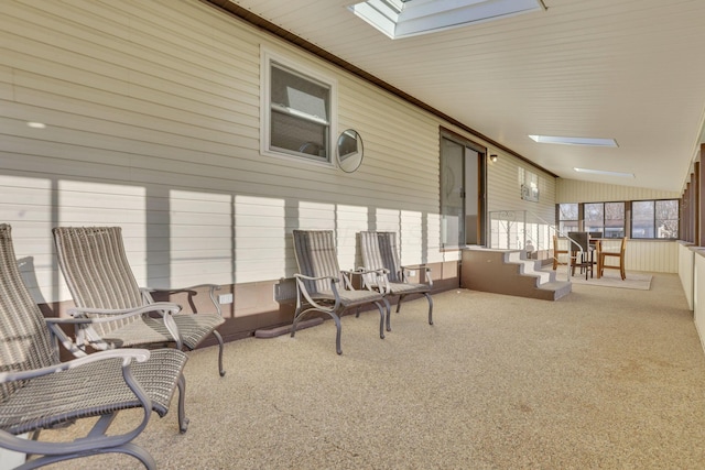 sunroom / solarium with a skylight, carpet flooring, and high vaulted ceiling