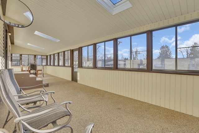 unfurnished sunroom featuring lofted ceiling with skylight, wooden walls, plenty of natural light, and carpet floors