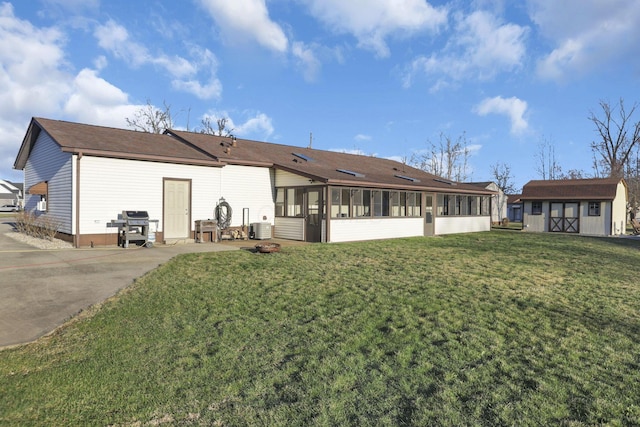 back of property featuring central air condition unit, a yard, a storage shed, an outdoor structure, and a sunroom
