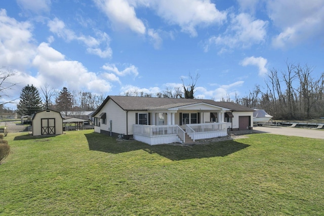 view of front of home featuring a front lawn, a porch, a storage shed, a garage, and driveway