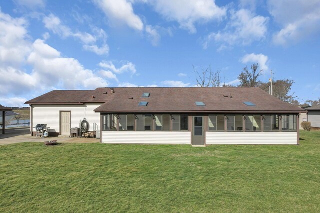 rear view of property featuring a yard, roof with shingles, a patio, and a sunroom